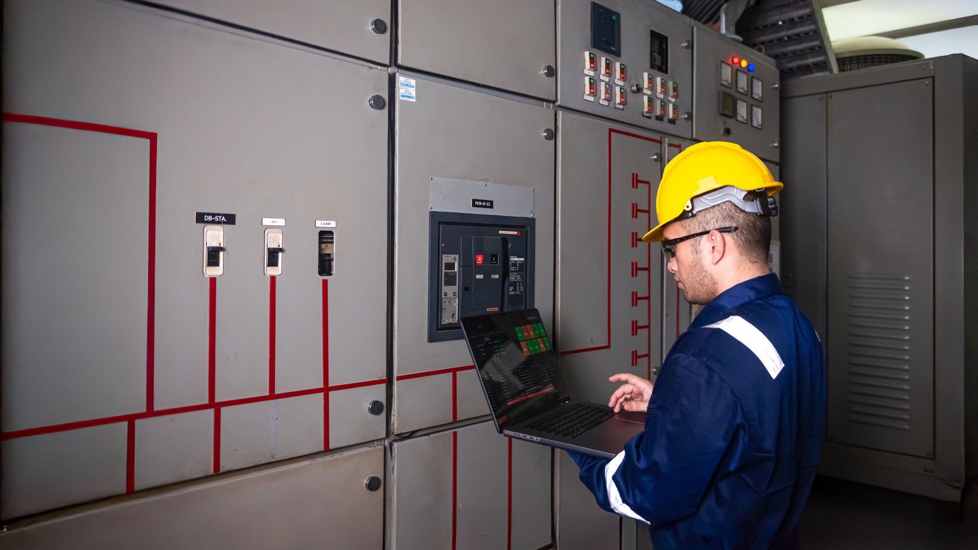 Electrical engineers check the operation of the main electrical control panels and switches, record values on tablets, electrician inspect the electrical systems in the factory.